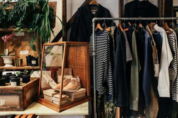A stylish boutique clothing rack featuring diverse apparel and accessories in a cozy, natural setting.
