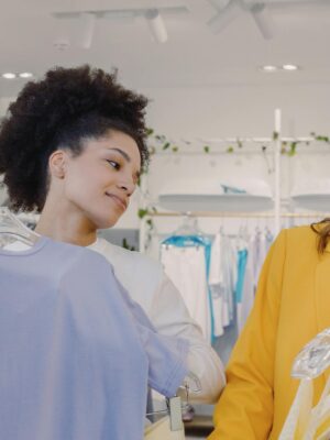 Two women explore fashion choices in a modern boutique, enjoying shopping together.