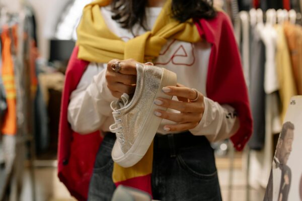 Woman shopping in store holding glittery sneakers. Fashionable retail moment.